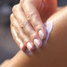Hand applying sunscreen to arm